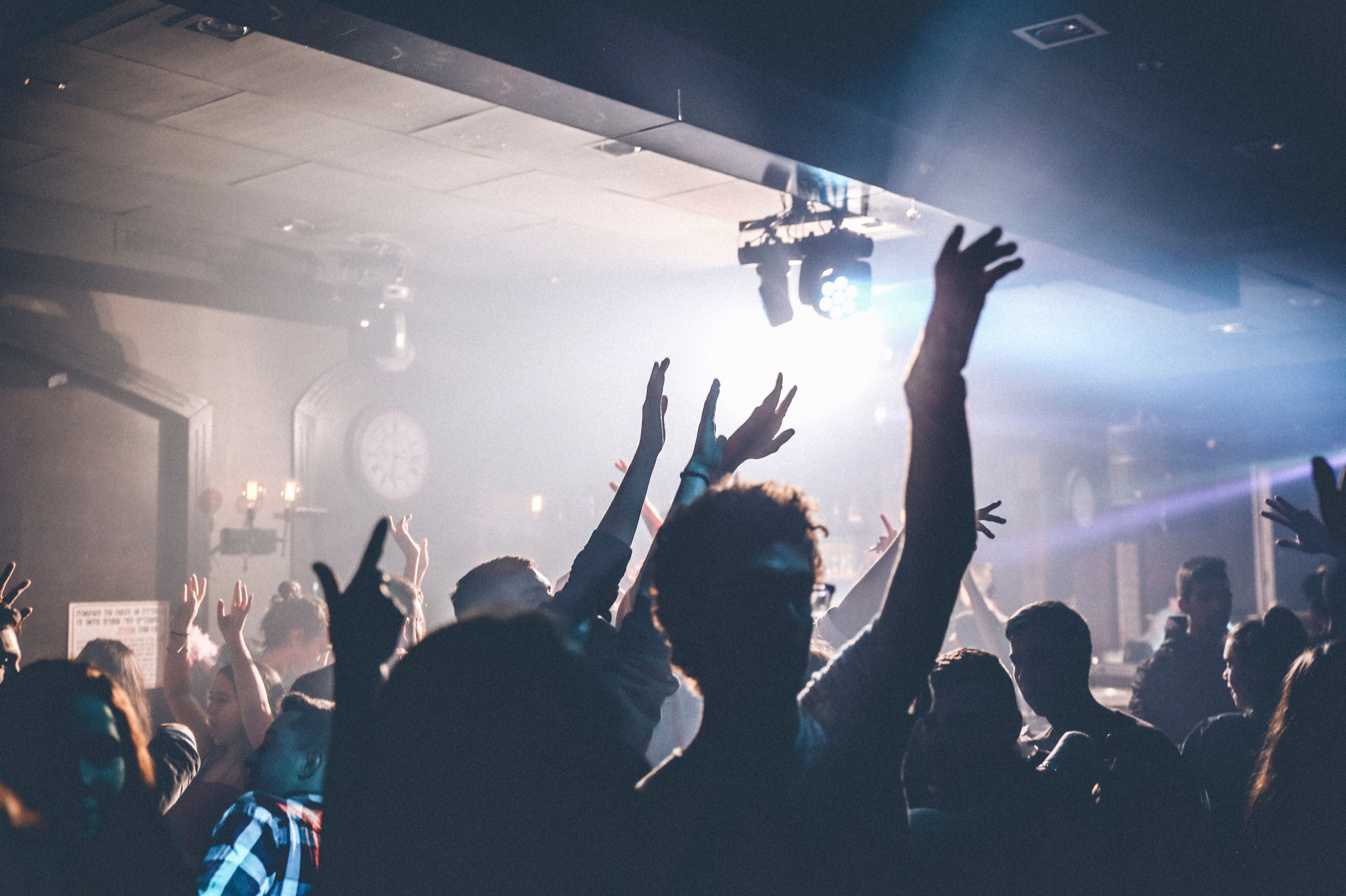 A packed nightlife crowd with their hands in the air